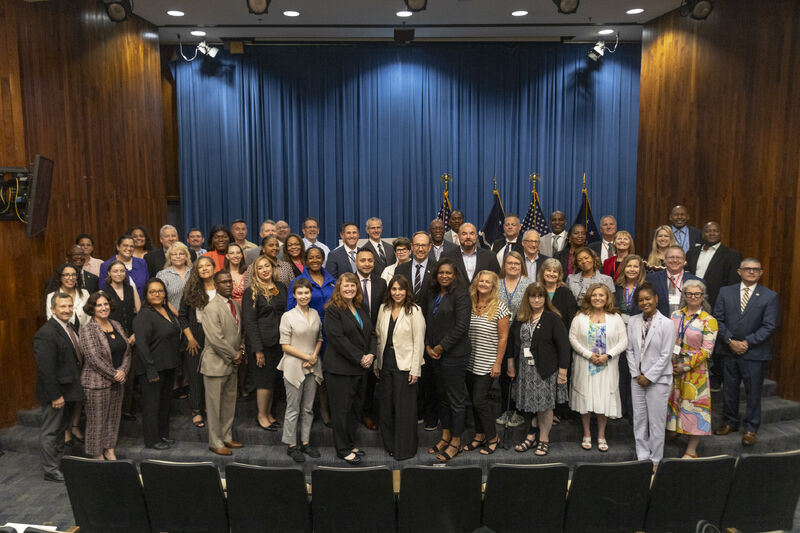 Group of individuals from the Federal Executive Boards gathered at the stage in an auditorium during a strategic meeting. 