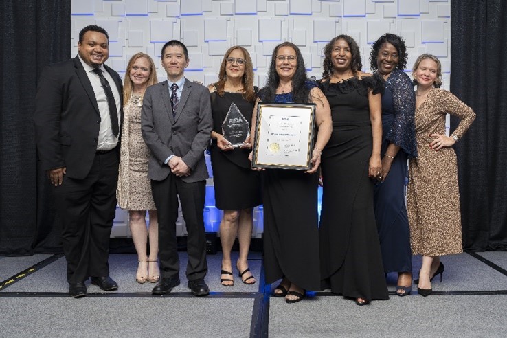 8 individuals from the Office of the Chief Financial Officer stood on the stage with two individuals held the AGA Certificate of Excellence in Accountability Reporting award.